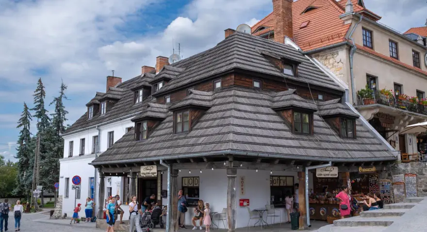 Kazimierz Dolny rynek tętni życiem. Ludzie spacerują, kupują lody i gofry pod urokliwymi, drewnianymi dachami kamienic.