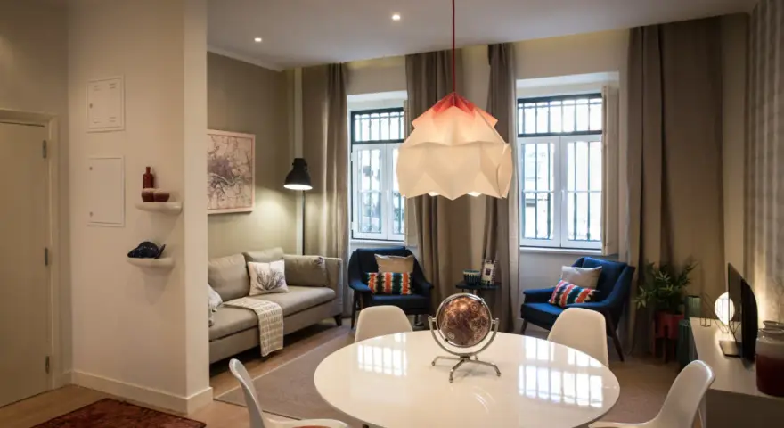 Una sala da pranzo moderna con tavolo bianco, sedie, divano, poltrone blu e un globo decorativo.