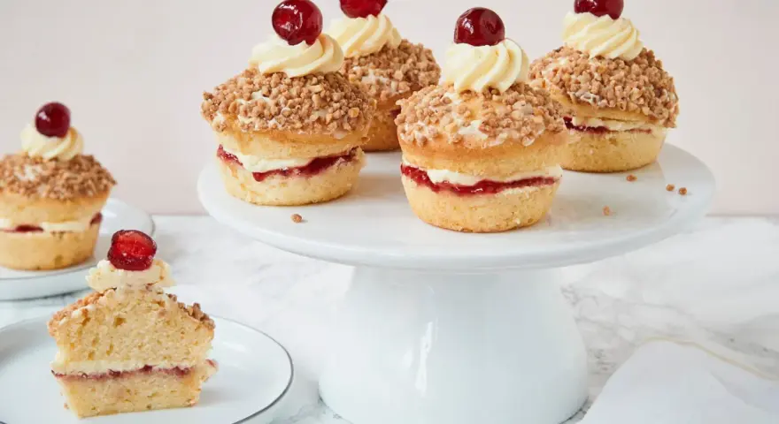 Frankfurter Kranz Muffins: kleine Kuchen mit Buttercreme, Marmelade und Mandelsplittern, gekrönt von einer Kirsche.