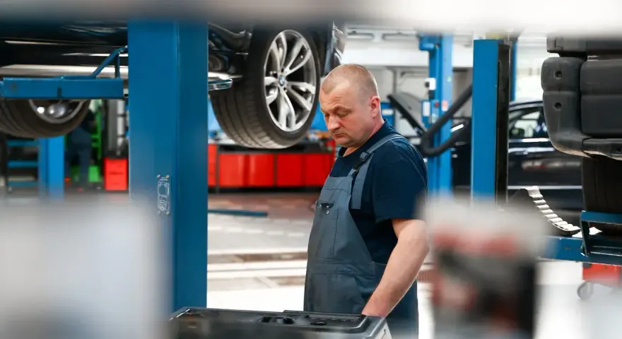 Mechanik w warsztacie, samochód na podnośniku. Sprawdza sprzęt do dynamiczna wymiana oleju dsg cena.