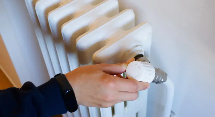 Ajustando el termostato de un radiador para optimizar la calefacción central en comunidades de vecinos.