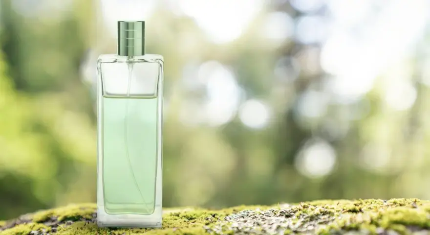 Elegancki perfum zielona herbata w szklanej butelce, stojący na mchu.