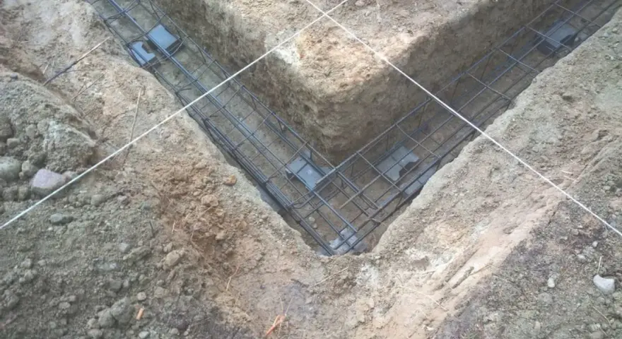 Zbrojenie fundamentów prefabrykowanych w wykopie. Stalowe pręty tworzą siatkę, gotową do zalania betonem.