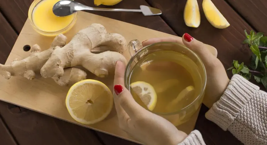 Kobieta pije herbatę z imbirem i cytryną, która pomaga w dolegliwościach w ciąży.