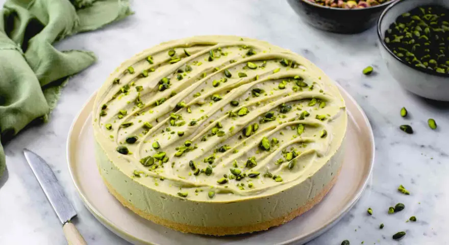 Cheesecake al pistacchio cremosa, decorata con granella verde brillante. Un dolce invitante pronto per essere gustato.