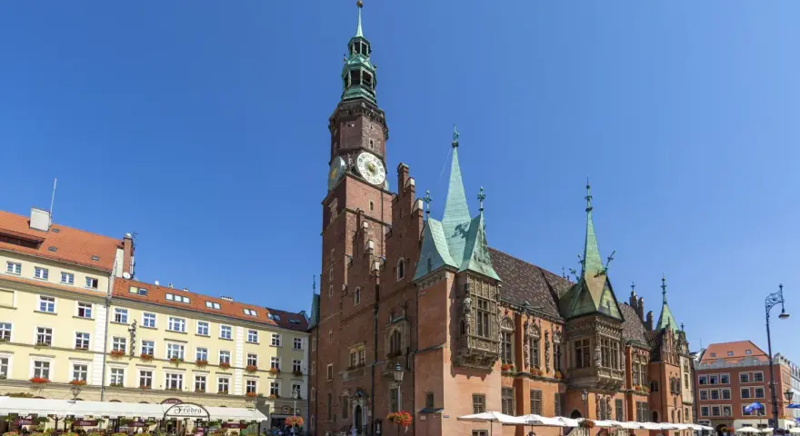 Rynek we Wrocławiu z Ratuszem, gdzie mieści się muzeum sztuki mieszczańskiej. Wokół kawiarnie i ludzie spacerujący.