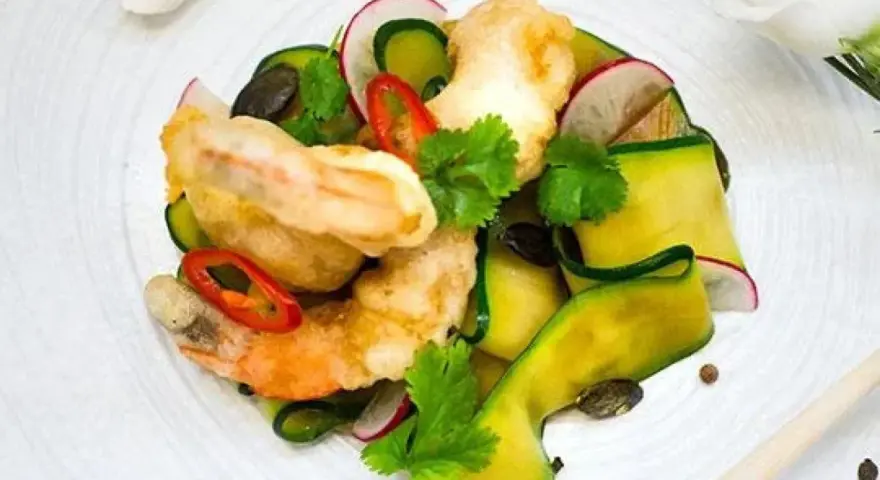 Chrupiące tempura do krewetek z cukinią, rzodkiewką i chili na białym talerzu.