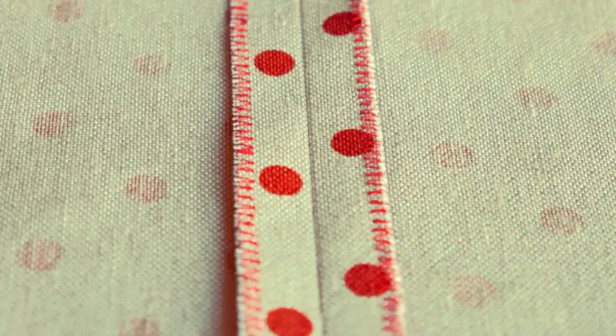 Tessuto a pois rossi con cucitura a punto sopraggitto a mano che crea un dettaglio decorativo.