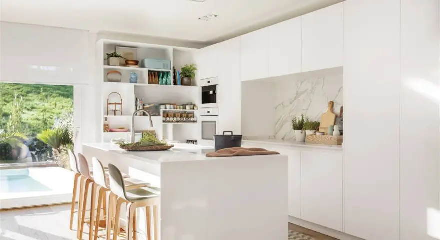 Cocina blanca moderna con isla central, estanterías abiertas y vistas al jardín. Ideas para decorar pared cocina blanca con estilo minimalista.