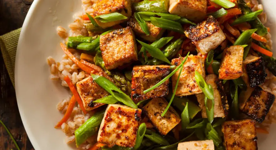 Chrupiące kostki tofu z warzywami i kaszą. Tofu to wszechstronny produkt roślinny, idealny do dań azjatyckich.