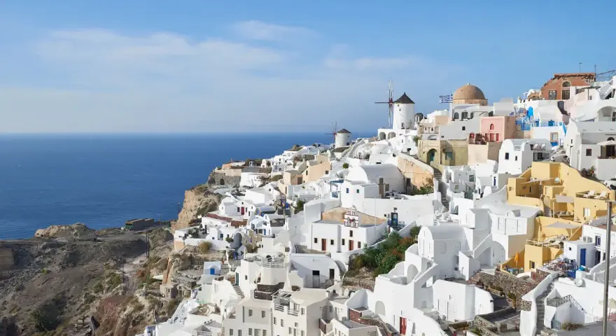 Malownicze białe domy Santorini wznoszą się na klifie nad błękitnym morzem. Wiatraki i kopuły kościołów dodają uroku. Idealne miejsce na rejs promem z Krety.