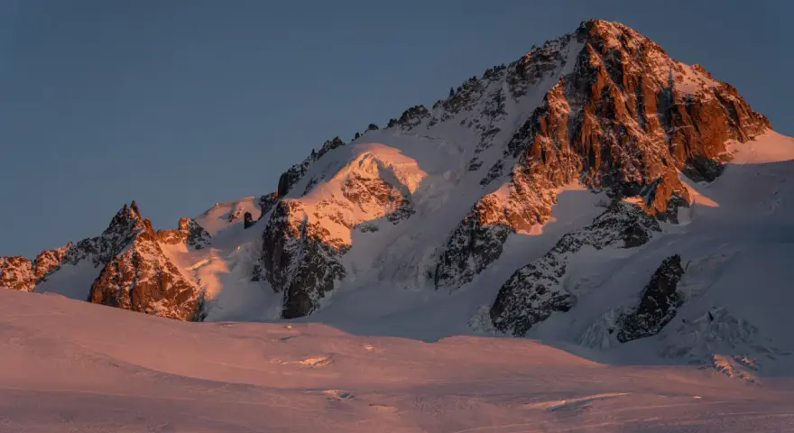 Ośnieżone szczyty Alp o wschodzie słońca, oświetlone złotym blaskiem. Widok na trasę Haute Route, gdzie lodowce i skaliste zbocza tworzą majestatyczny krajobraz.