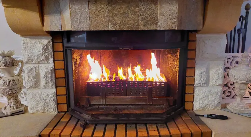 Chimenea de leña con llamas vibrantes. El fuego ilumina el interior de la chimenea, creando un ambiente acogedor. Los pellets en la base de la chimenea se queman, alimentando las llamas.