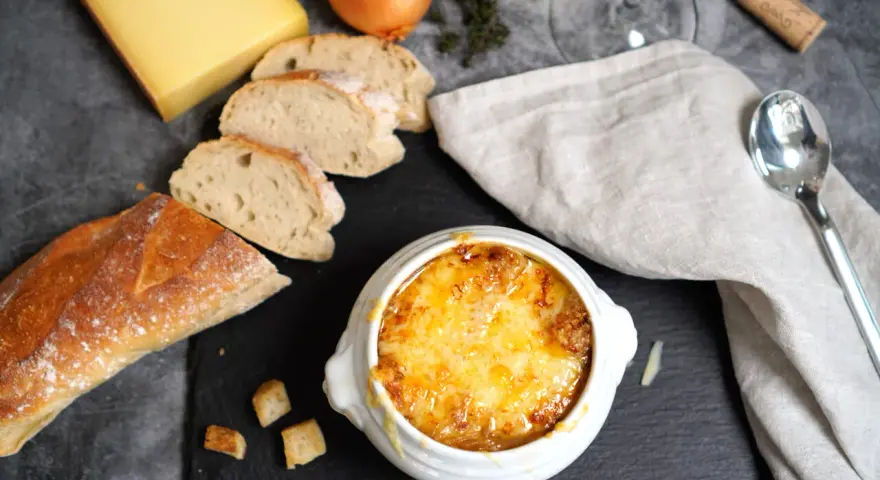 Herzhaftes Zwiebelsuppen-Rezept: goldbraun überbackene Suppe mit Käse, Baguette und Zwiebeln.
