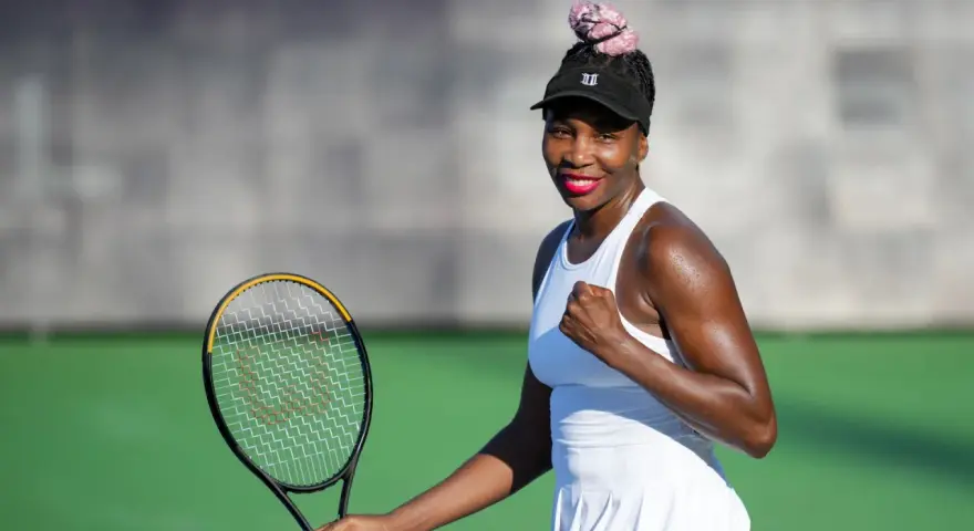 Venus Williams, con su estatura imponente, celebra un punto en la cancha de tenis.