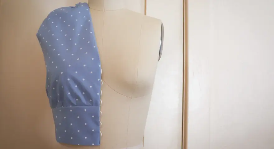 Mannequin de couture présentant un corsage bleu à pois blancs, esquisse d'une future robe de mariée couture.