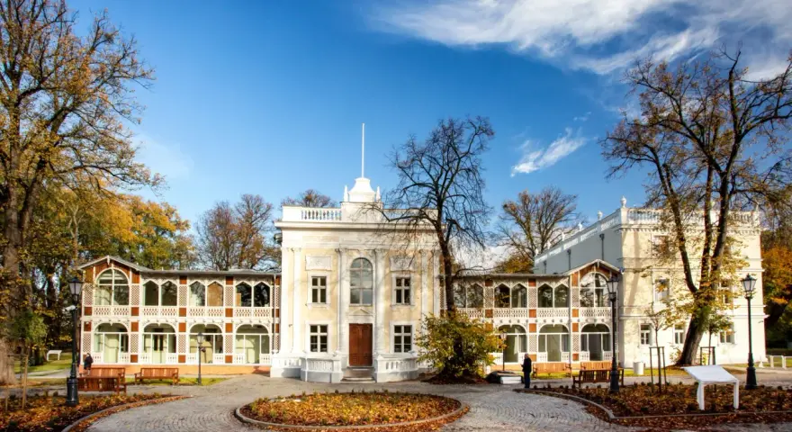 Brzeźno dom zdrojowy, zabytkowy budynek z arkadowymi werandami, otoczony jesiennym parkiem.