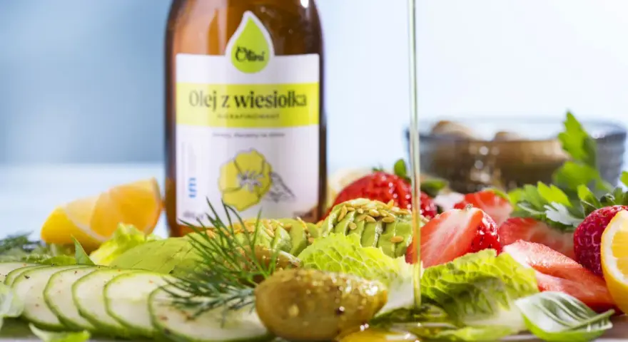 Butelka oleju z wiesiołka i sałatka z awokado, truskawek, ogórka i cytryny.