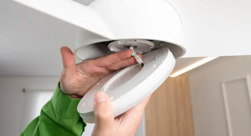 Man installing a ceiling fan with light. Close-up of hands connecting wires to the light fixture.