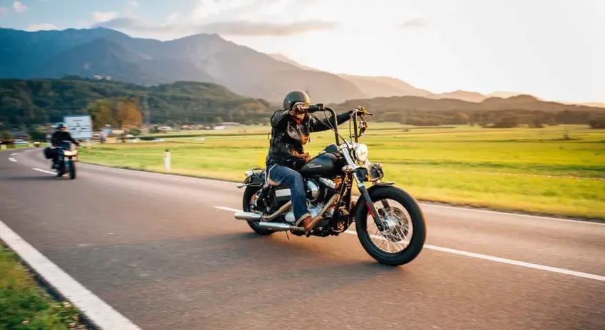 Motociclista in viaggio su una strada panoramica, un'atmosfera da European Bike Week con montagne sullo sfondo.