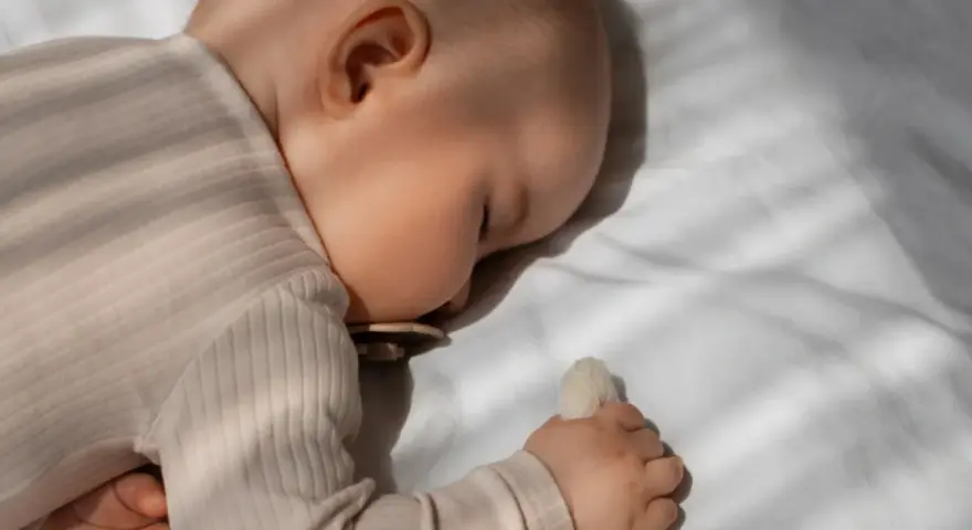Bambino dorme sereno, forse grazie alla melatonina per bambini iperattivi, con ciuccio e peluche.