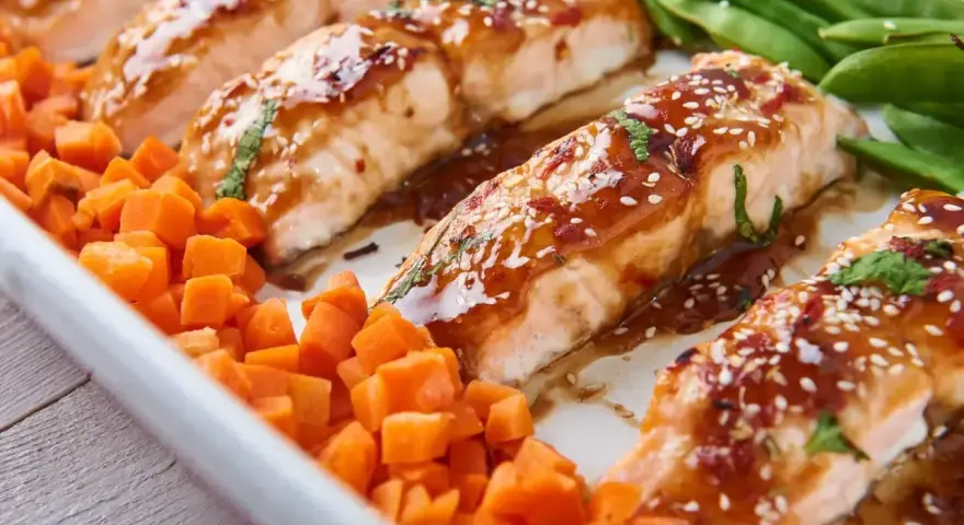 Jak przyrządzić łososia na obiad? Pieczony łosoś w sosie teriyaki z sezamem, podany z marchewką i fasolką szparagową.
