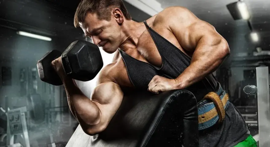Mężczyzna ćwiczy biceps, napinając mięsień dwugłowy ramienia podczas podnoszenia hantli.