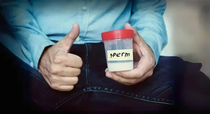 Mężczyzna pokazuje kciuk w górę, trzymając pojemnik z napisem "sperm". Zawartość pojemnika ma prawidłowy kolor spermy.
