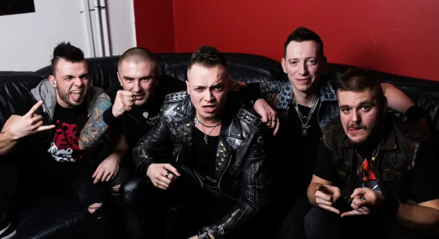 Pięciu mężczyzn w skórzanych kurtkach i z rockowymi fryzurami, jakby gotowi na nocny koncert. Wyglądają jak zespół nocny kochanek.