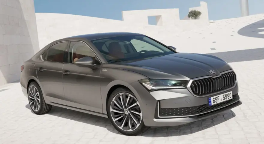 Szary sedan Skoda Superb, segment d, zaparkowany na tle nowoczesnej architektury.