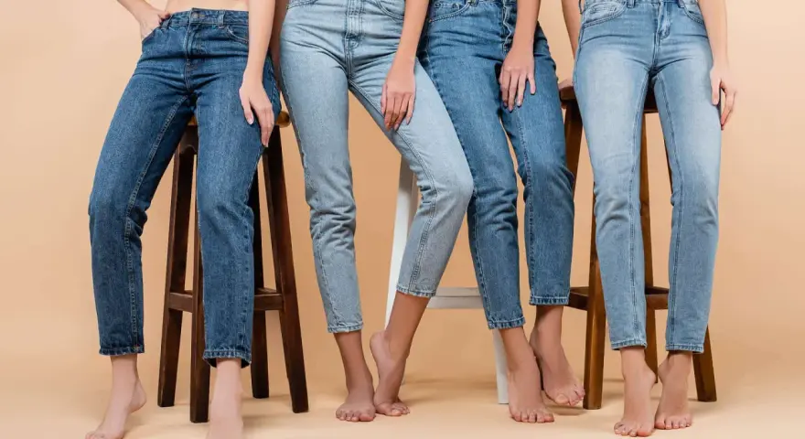 Cztery kobiety w różnych odcieniach jeansów siedzą na stołkach. Denim to materiał, który nigdy nie wychodzi z mody.