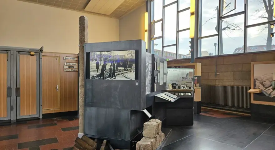 Ausstellung im "Palace of Tears" Berlin: Ein Stein, ein Bildschirm mit historischem Bild, und Ausstellungsstücke erinnern an die Teilung.