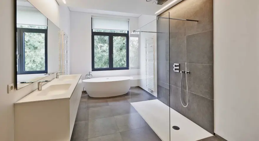 Salle de bain moderne avec douche à l'italienne aux galets hydrofuges, baignoire îlot et double vasque.