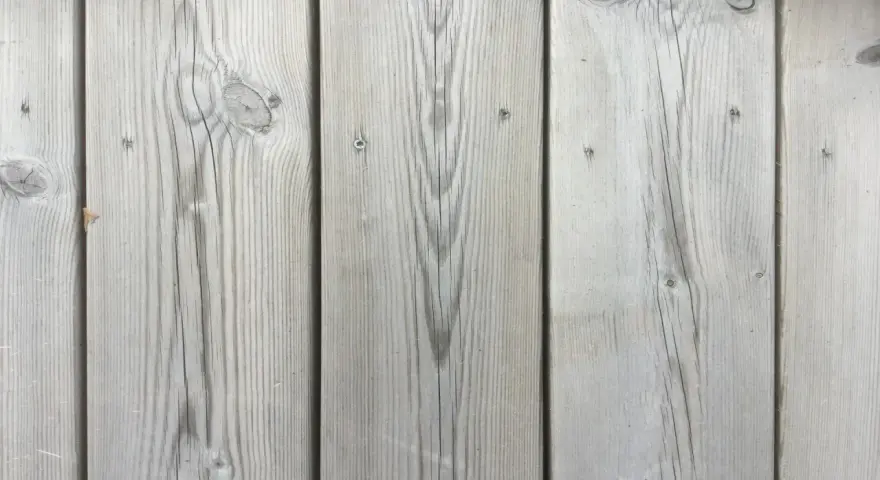 Grå träplankor på en kisel altan i Sverige. Vackert åldrat trä med synliga ådringar och kvistar.