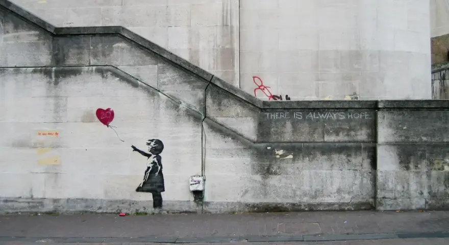 La célèbre œuvre de Banksy, "Girl with Balloon", sur un mur de pierre. Une petite fille lâche un ballon en forme de cœur rouge.