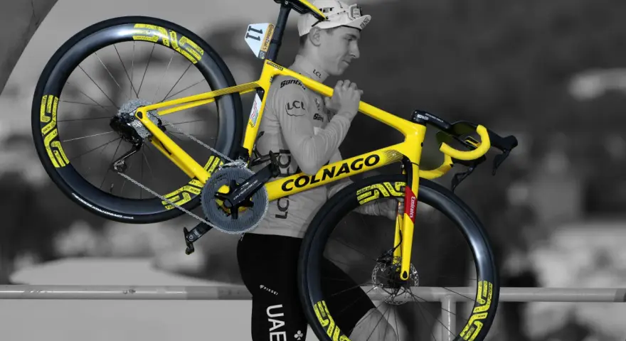 A cyclist carries his bright yellow Colnago bike, ready for Tour de France training.