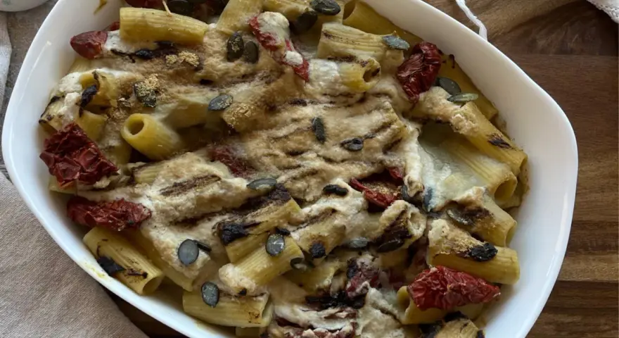 Piatto di pasta con carciofi alla siciliana, pomodori secchi e semi di zucca, gratinata al forno.