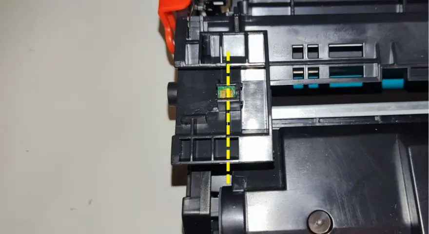 Widok z bliska na chip w tonerze HP, zaznaczony żółtą linią. Pokazuje, jak przełożyć chip w tonerze HP.