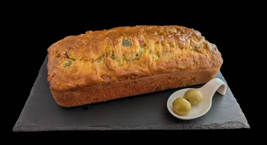 Un délicieux cake jambon olive, doré et moelleux, servi avec deux olives vertes sur une cuillère.