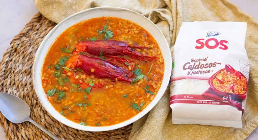 Un delicioso arroz caldoso con gambas rojas, adornado con perejil fresco. La bolsa de arroz SOS "Especial Caldosos y melosos" promete una preparación perfecta.