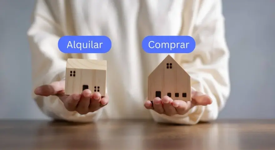 Manos sostienen casas de madera, una con "Alquilar" y otra con "Comprar", planteando la duda de si vivir de alquiler toda la vida es la mejor opción.