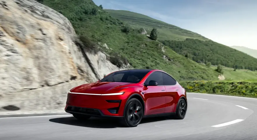 Czerwony Tesla Model Y Performance na krętej drodze w górach.