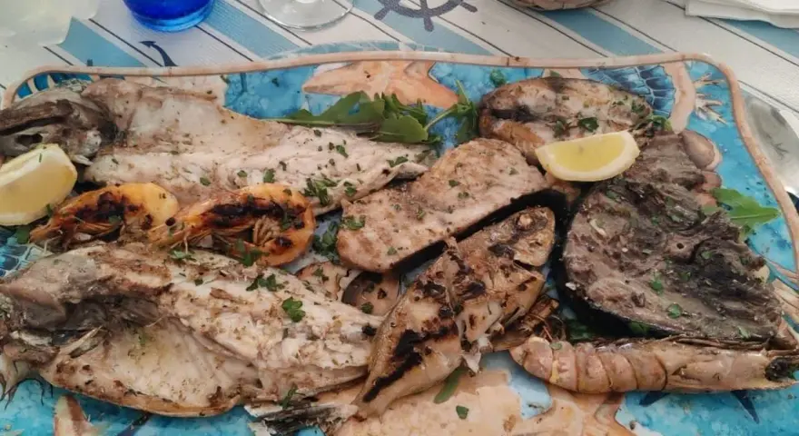 A platter of grilled fish and shrimp garnished with lemon and parsley.