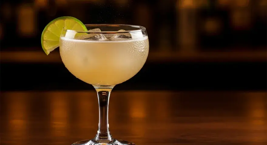 En kyld Moscow Mule med limeklyfta, is och bubblor på en träyta.