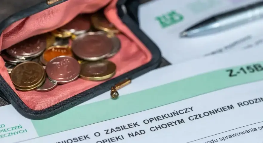 Portmonetka z monetami leży obok formularza ZUS Z-15B, który dotyczy wniosku o zasiłek opiekuńczy.