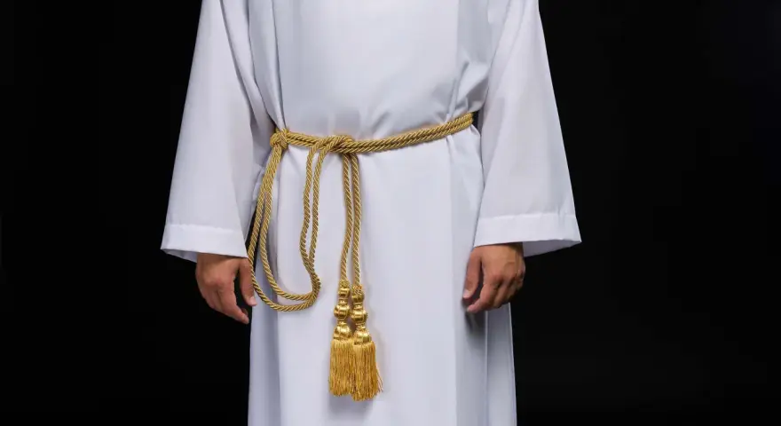 Szata proboszcza w kolorze białym, przepasana złotym sznurem z ozdobnymi chwostami.