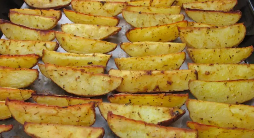 Des pommes de terre rôties au four croustillantes, dorées et assaisonnées, disposées sur une plaque de cuisson.