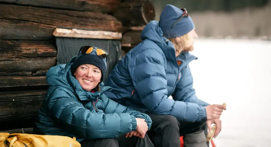 Zwei Personen in warmen 700 cuin Daunenjacken genießen eine Pause im Freien. Die Jacken halten sie bei kühler Temperatur angenehm warm.