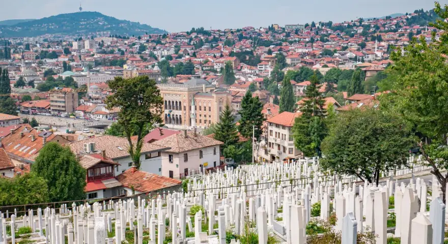 Widok na cmentarz z białymi nagrobkami i panoramę Sarajewa. Warto zobaczyć to miejsce, by poczuć historię miasta.