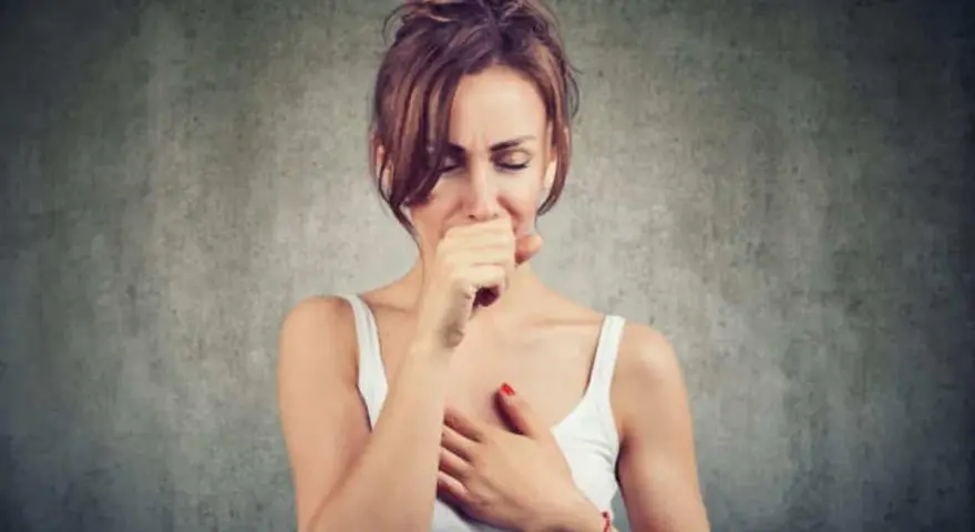 Mujer tosiendo y con dolor de cabeza, quizás por vapear.